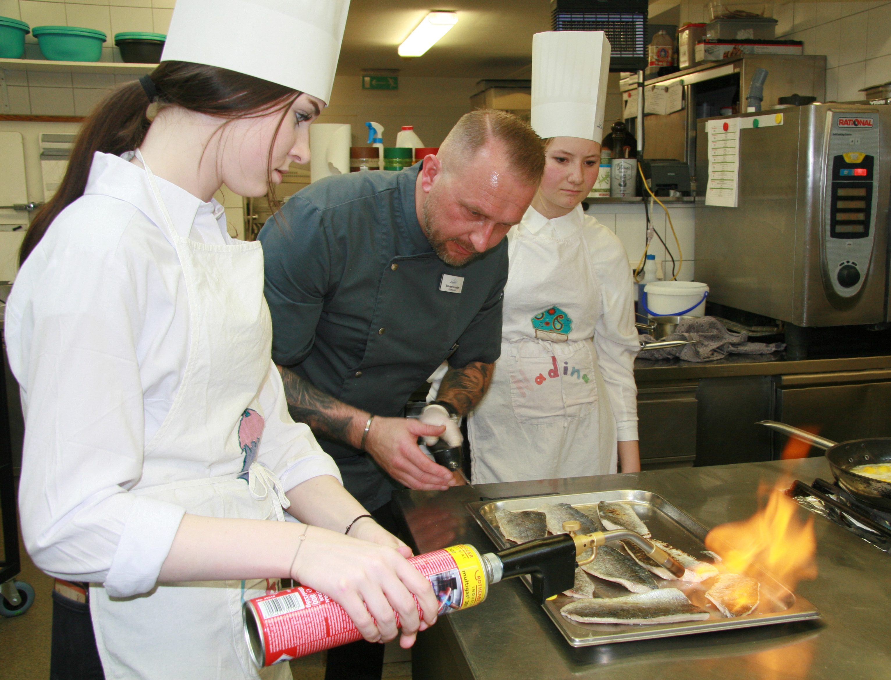 Küchenchef Eduard Livader hilft den Schüler_innen beim Flambieren.