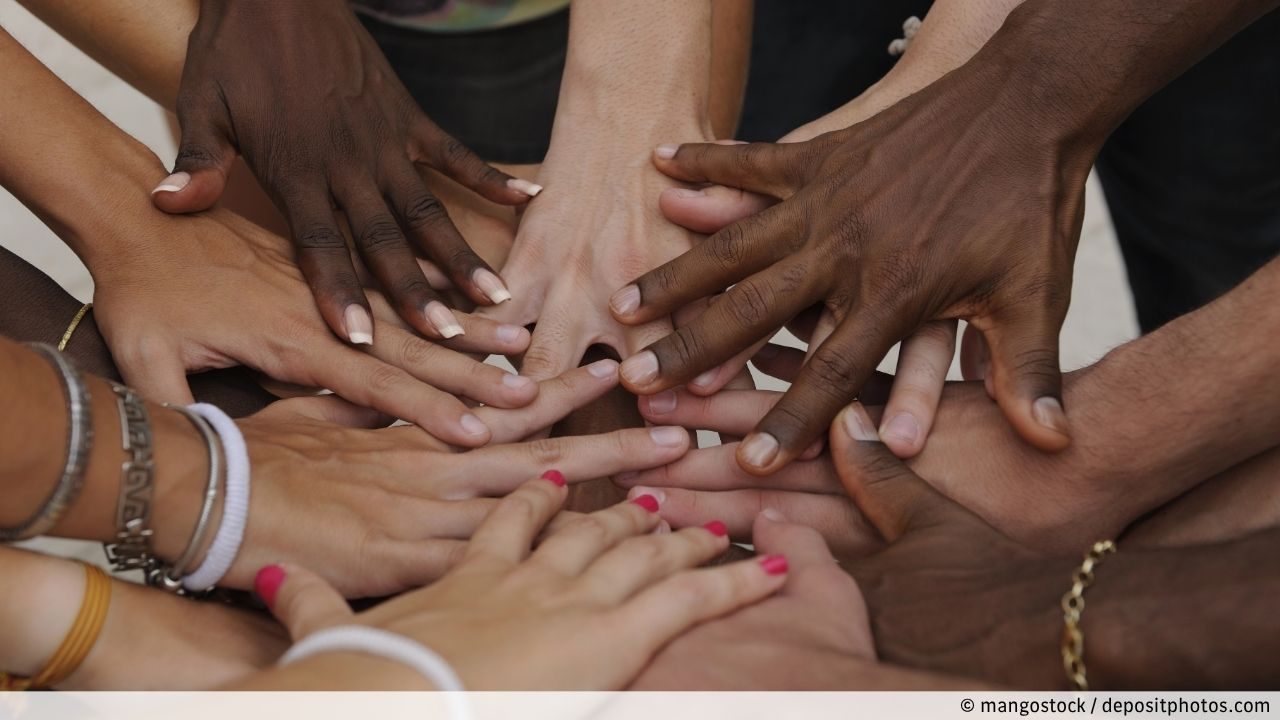 Ausgestreckte Hände unterschiedlicher Menschen aus verschiedenen Orten der Welt die sich berühren als Zeichen der Diversität, Nächstenliebe und Zusammenhalt gegen Diskriminierung und Rassismus