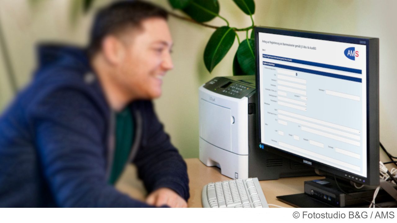 Unternehmer sitzt vor dem Computer und füllt ein AMS Online-Formular aus