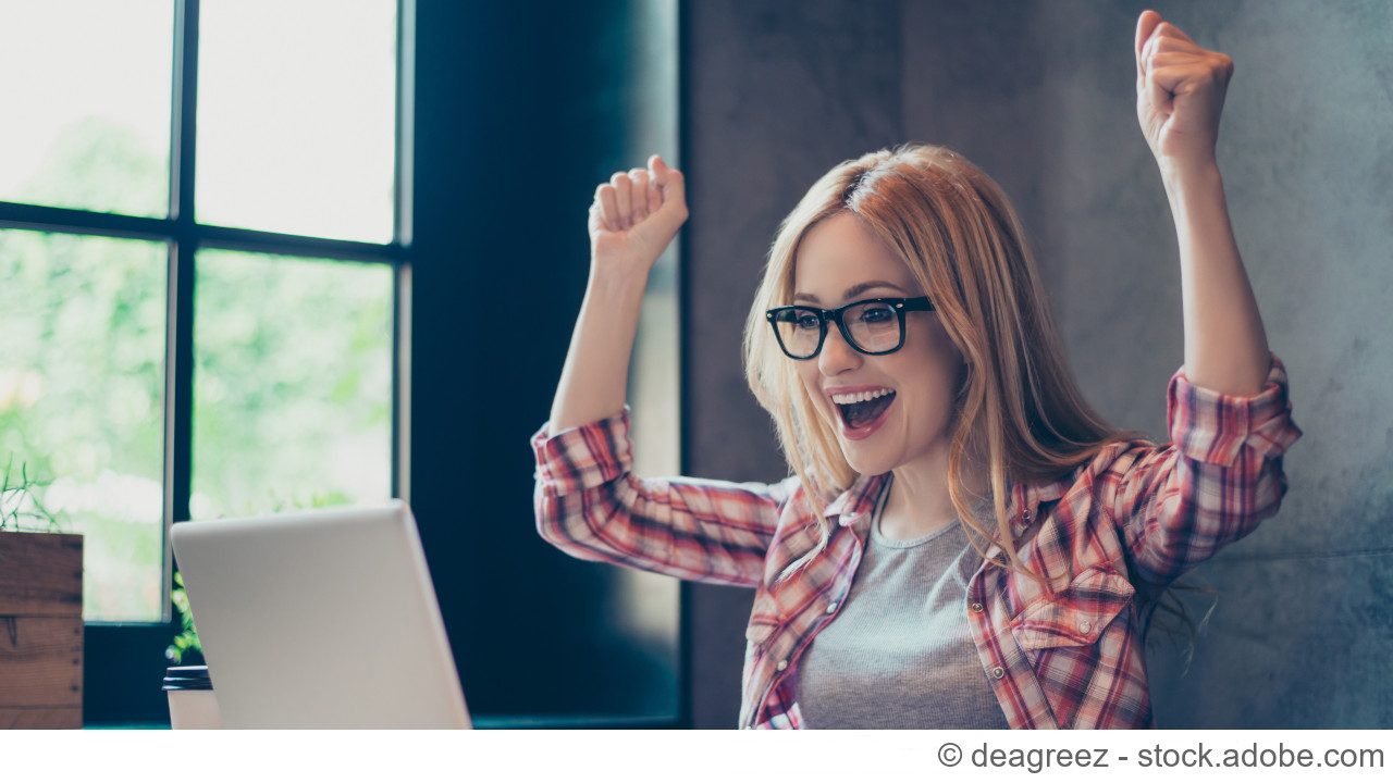 Frau vor Laptop freut sich