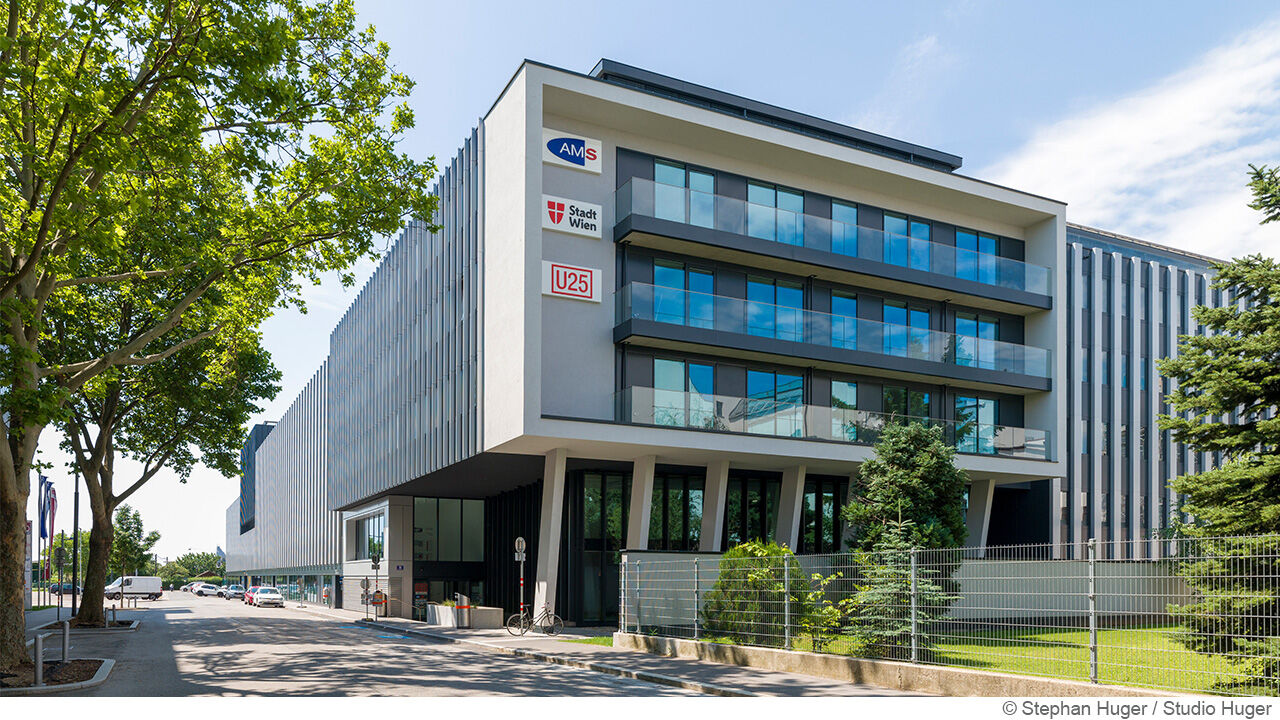 dreistöckiges Bürogebäude mit 3 Logos auf der linken Hausseite 